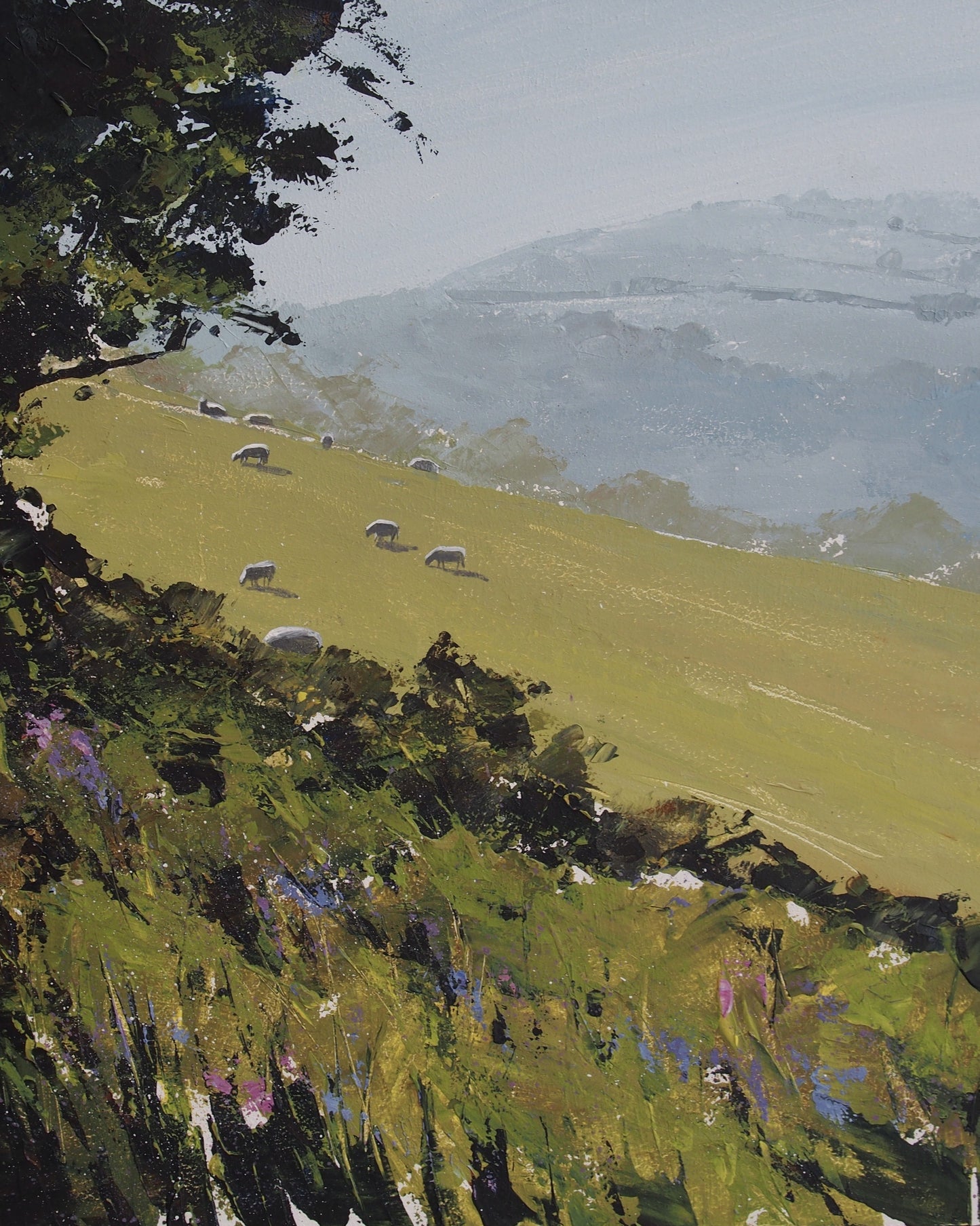 Landscape painting of a green hillside with grazing sheep, dark tree branches at the top left, and hazy blue mountains in the background.